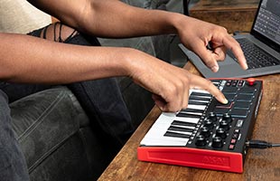 close-up side image of musician's hands playing performance pads on Akai Professional MPK Mini Mk3
